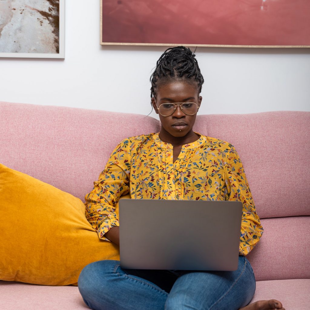 Concentrated black bussineswoman freelancer working on startup project and sitting on couch