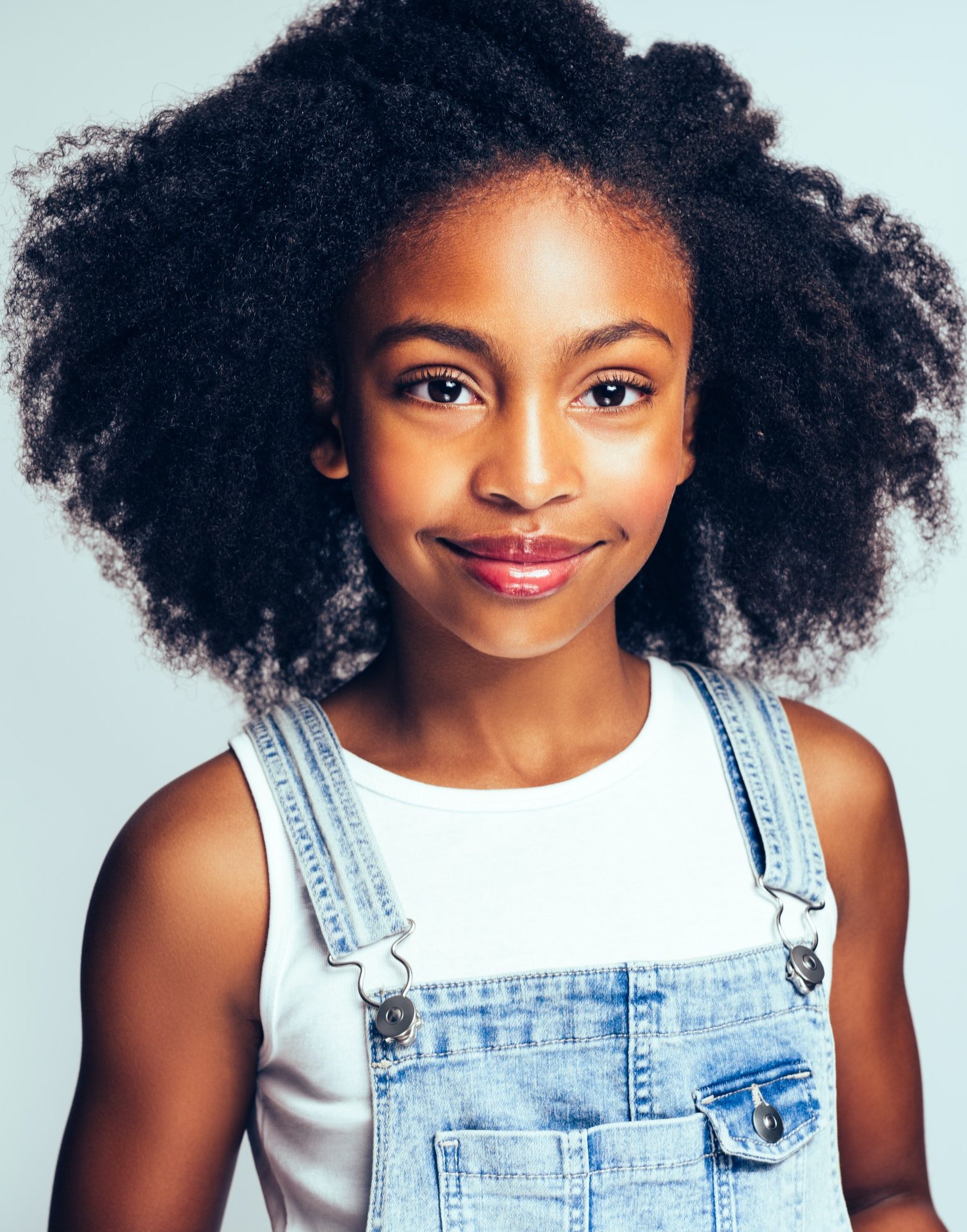 Young African girl smiling against a gray background